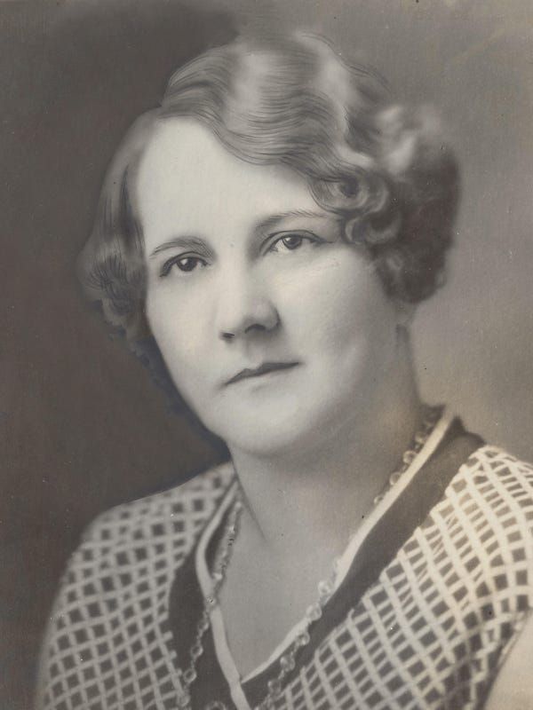 Black and white portrait of a middle aged woman wearing a checked shirt and a necklace